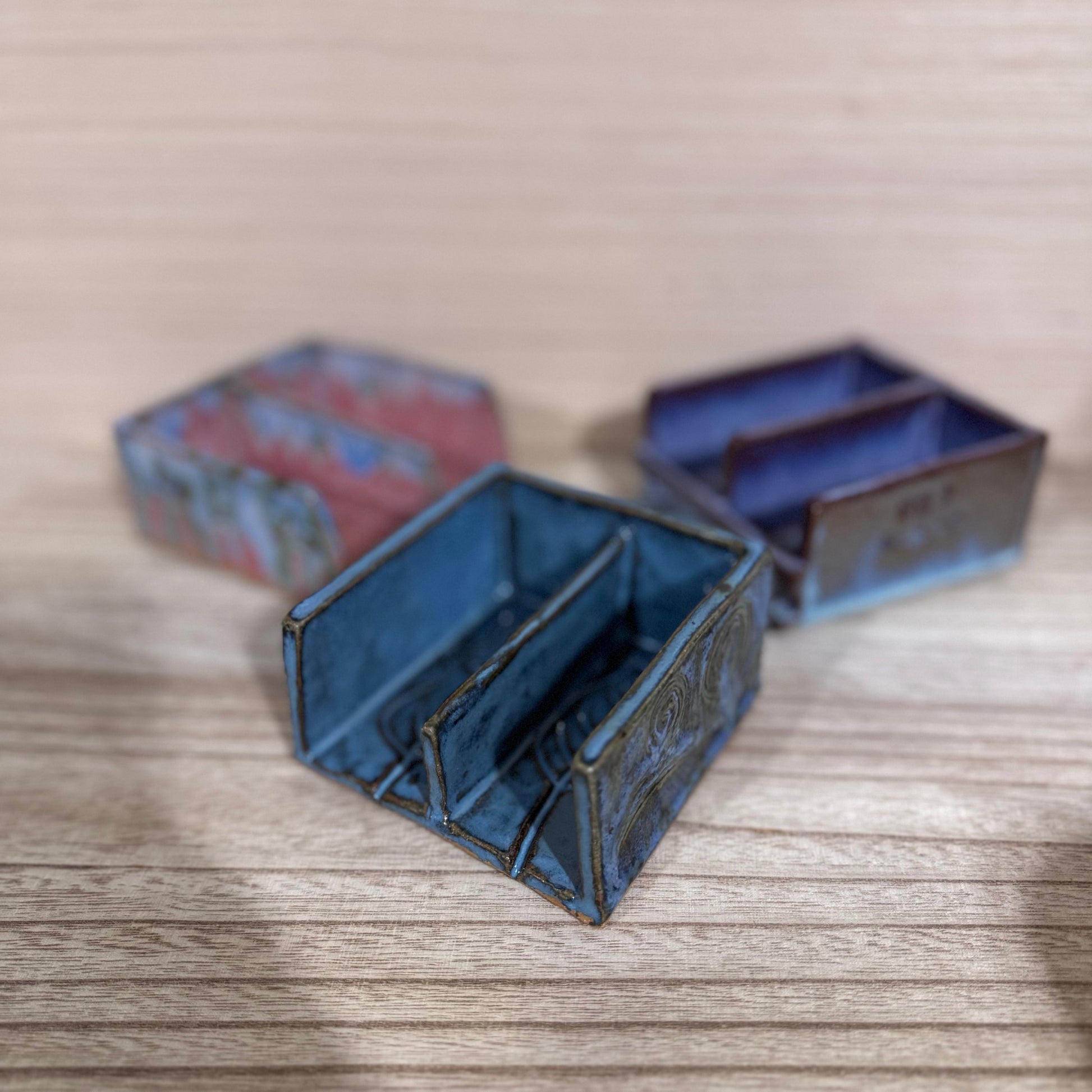 Three ceramic soap dishes on a wooden surface with a blurred background
