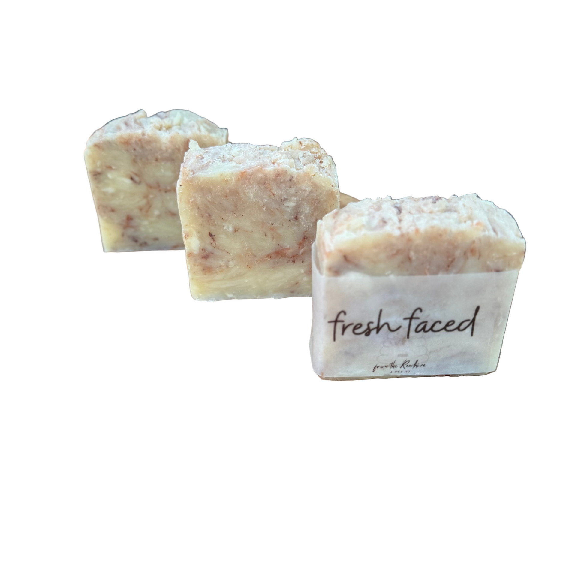 Three bars of soap labeled 'fresh faced' on a wooden surface with a natural background.